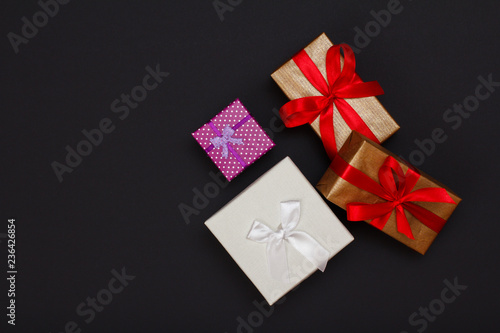 Gift boxes with ribbons on black background. © Vitalii M