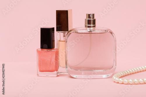 Women perfumes and cosmetics on a pink background.