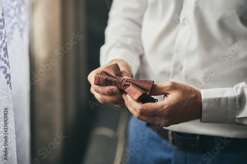 businessman putting on bow tie,man butterfly clothes,groom getting ready in the morning before wedding ceremony