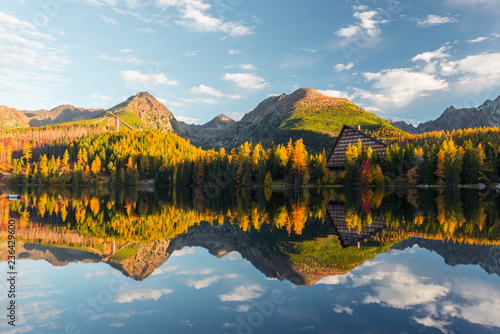 Picturesque autumn view of lake Strbske pleso in High Tatras National Park  Slovakia. Clear water with reflections of orange larch and high mountains on background. Landscape photography