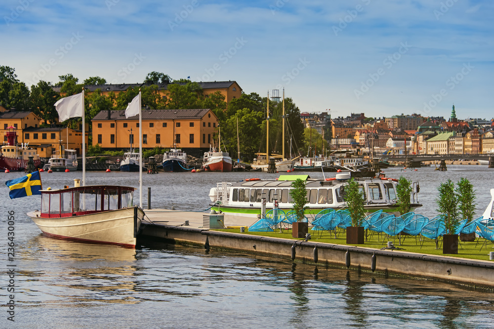 pleasure boats moored at a pier with city cafe terrace on it in Stockholm city center