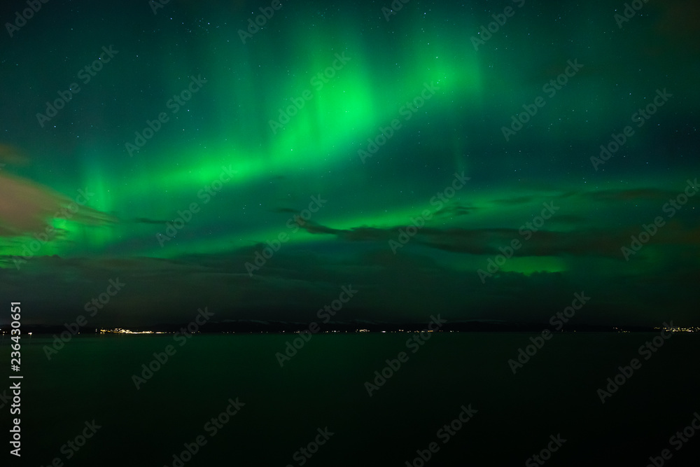 Green Aurora Borealis on night sky.