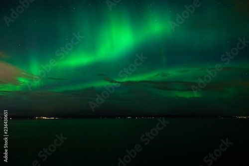 Green Aurora Borealis on night sky.