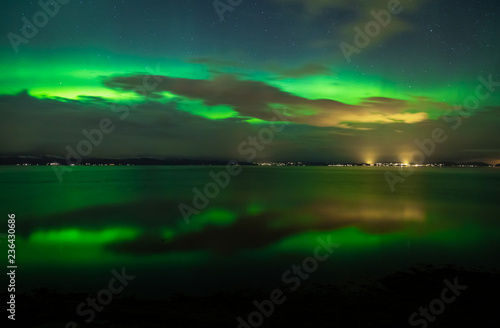 Green Aurora Borealis on night sky.