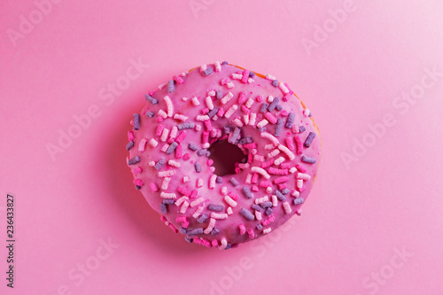 Single round donut on pink background.