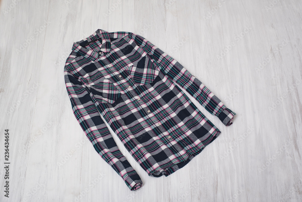 Fashionable concept. Checkered shirt on a wooden background. Female wardrobe Fashionable concept. Checkered shirt on a wooden background. Female wardrobe