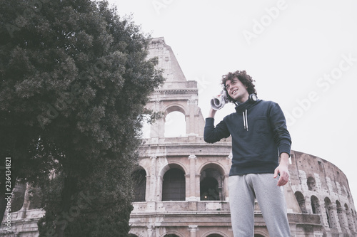 Vintage looking image of handsome young sportsman relaxing after training wiping sweat with a towel in front of Colosseum in Rome