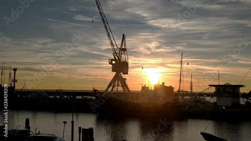 Dolly shot of a sun set in the harbour of Harlingen. Tug boat Holland and a vintage crane, backlight. photo