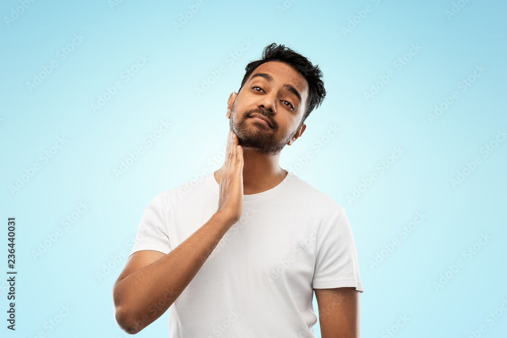 grooming and people concept - indian man touching his beard over blue background grooming and people concept - indian man touching his beard over blue background