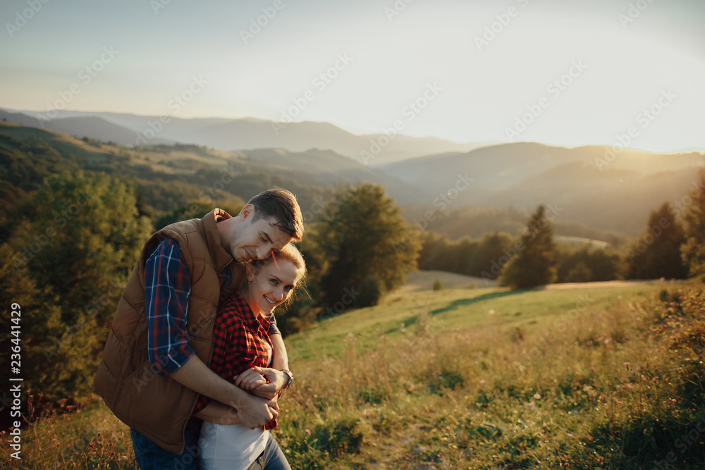 Young pretty couple hugging and smiling at the lake at sunset Young pretty couple hugging and smiling at the lake at sunset