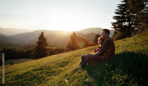 Young pretty couple hugging and smiling at the lake at sunset