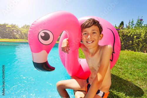 Happy boy with swim ring relaxing by the pool