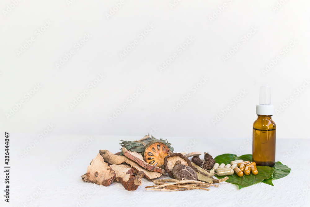 Dried herbs and Herbal medicine pill and Natural extracts cosmetics in a bottle on a white wooden table and white background, image with copy space for text or image.