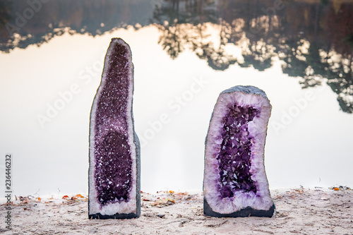 2 large amethyst crystals geodes near the water of a lake during sunset