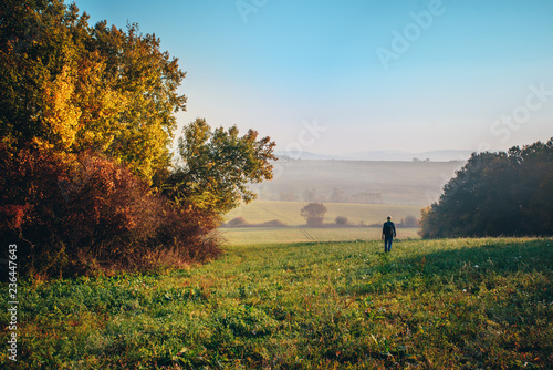 Man walking alone in colorful morning autumn landscape