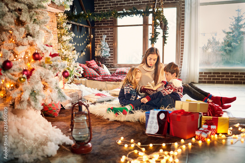 Mom and children are reading a book on Christmas Day. © Studio Romantic