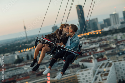 Young couple in love, riding chairoplane on a fairground