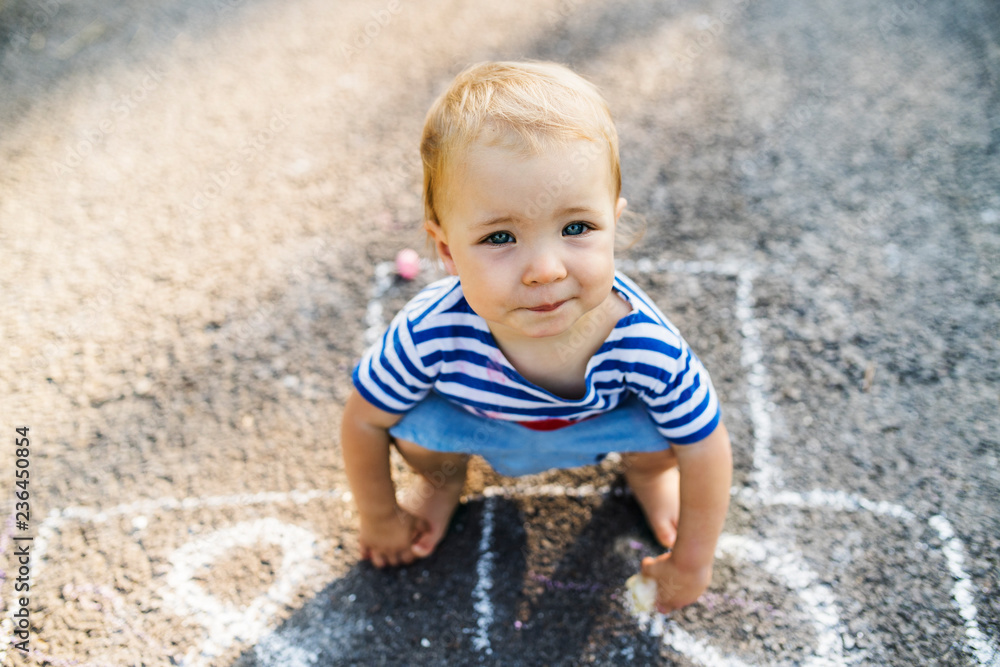 Portrait of baby girl crouching barefoot on asphalt Portrait of baby girl crouching barefoot on asphalt