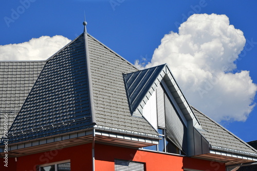 Dachgauben in Stehfalz-Zinkblechverkleidung am Ziegeldach eines Wohngeb  udes Regenrinne und Regenfallrohr