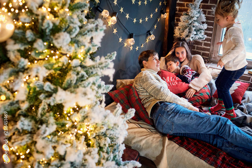 Mother and father with children playing at home on Christmas Day