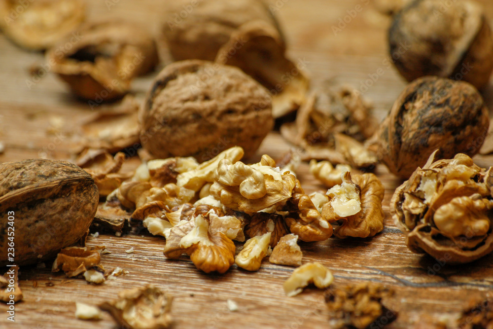 Walnuts and cracked walnuts on wooden table. Close-up, healthy food with rustic background.