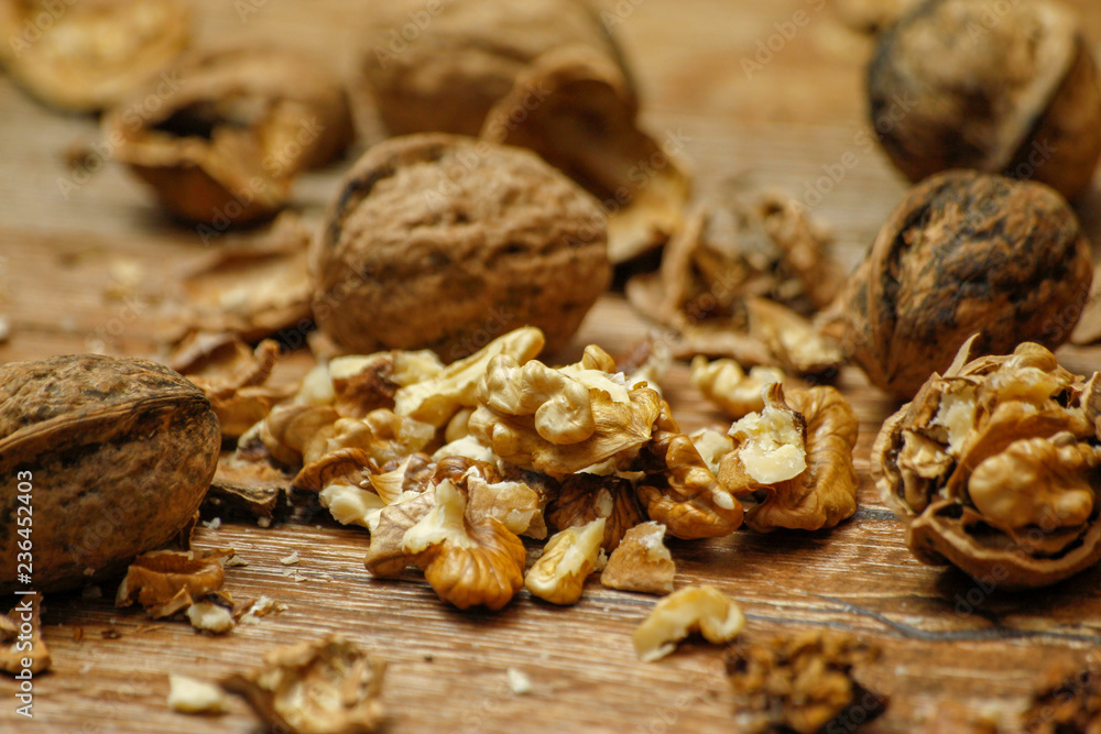 Fototapeta premium Walnuts and cracked walnuts on wooden table. Close-up, healthy food with rustic background.