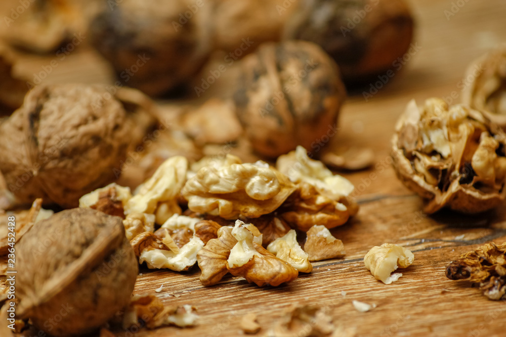 Walnuts and cracked walnuts on wooden table. Close-up, healthy food with rustic background. Walnuts and cracked walnuts on wooden table. Close-up, healthy food with rustic background.