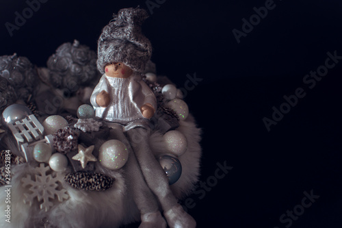 White fur Christmas wreath decoration for December with candles and happy elf figure and sled Holiday celebration, pine cone luxury postcard black wallpaper and background