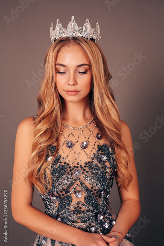 beautiful woman with long blond hair in luxurious evening dress with crown on her head