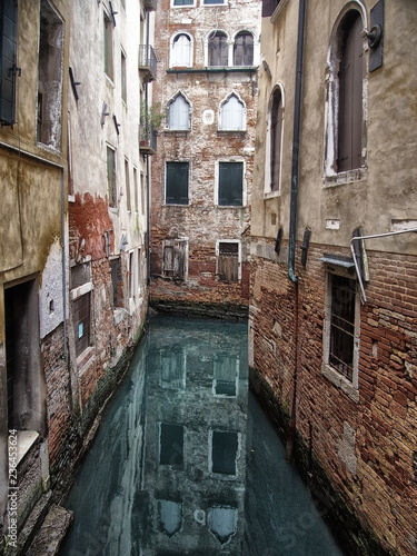 Fototapeta Naklejka Na Ścianę i Meble -  a quiet narrow canal in venice surrounded by picturesque ancient buildings reflected in the water