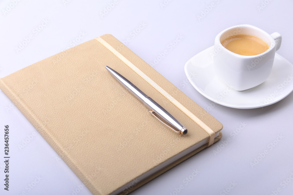 stylish notebook, ballpoint pen and white cup with a fragrant espresso coffee on the office desk. stylish notebook, ballpoint pen and white cup with a fragrant espresso coffee on the office desk.