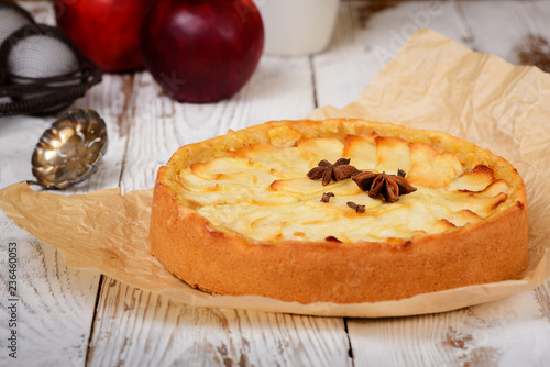 Traditional holiday apple pie. Baked dessert with anise, cloves and apples on light wooden background