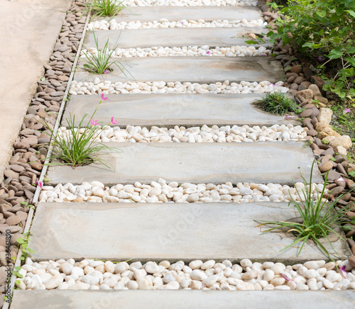 Landscape modern simple stone pathway in garden decoration with white,brown pebbles  and pink rain lily flowers