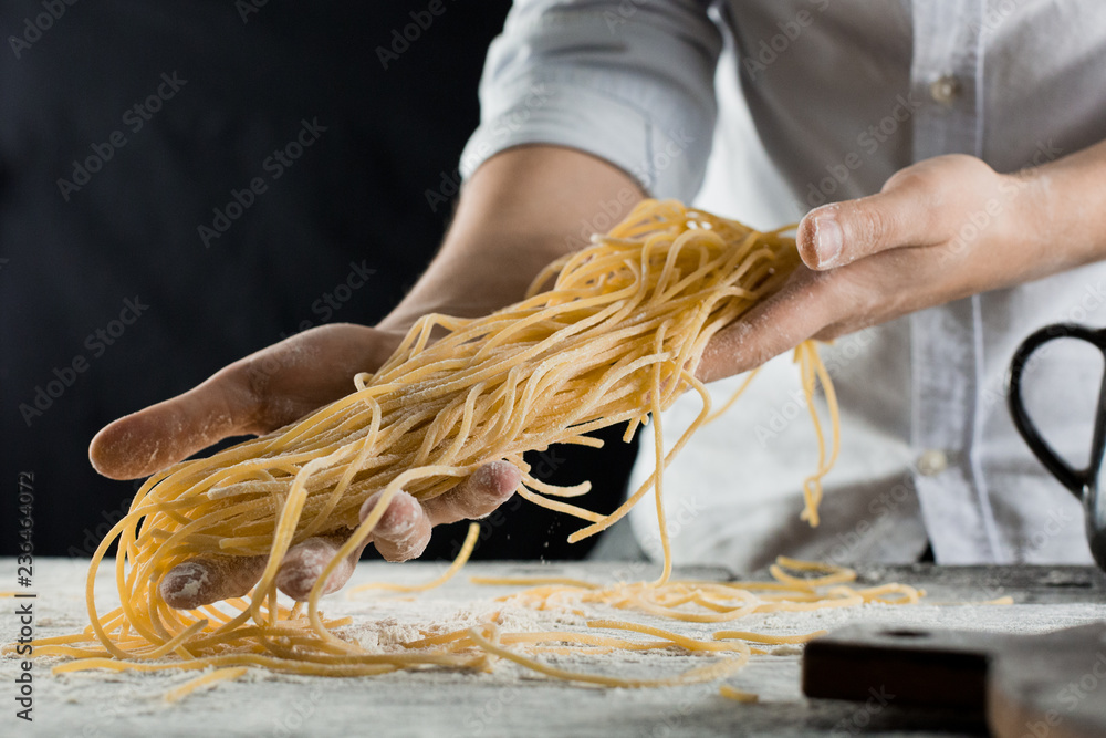 Obraz premium Cook holding freshly cooked spaghetti in the kitchen