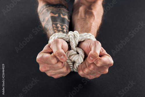 cropped view of male hands bound with rope isolated on black