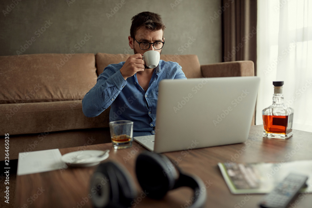 businessman is drinking coffee while working from a home .