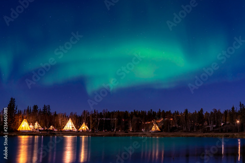 Group of Tipi with smooth water reflection under Northern light in Yellow Knife,