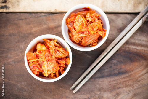 Kimchi cabbage in a bowl with chopsticks for eating on wooden table, Korean food