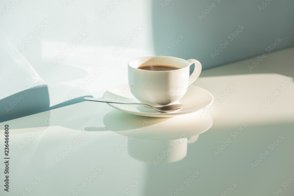 Cup of steaming coffee on seafoam green background in bright sunlight. Abstract photo of hot espresso drink on pale blue-green table and wall Cup of steaming coffee on seafoam green background in bright sunlight. Abstract photo of hot espresso drink on pale blue-green table and wall