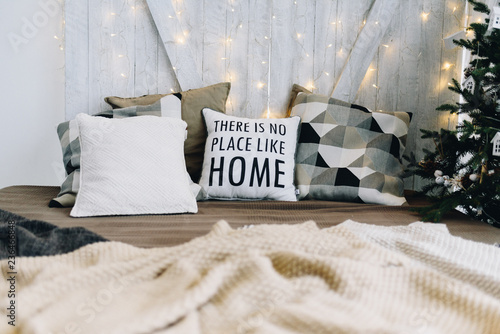 Very cozy and modern Christmas interior design idea with pillows and Christmas lights. Words on a pillow say "There is no place like home".