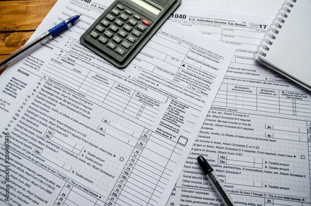 1040 tax form, pens, calculator and notepad on the table 1040 tax form, pens, calculator and notepad on the table