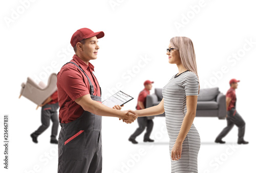 Mover shaking hands with a woman and movers carrying furniture in the back