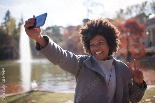 Afro woman having fun in the park with her smart phone, take a photo