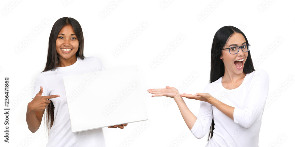 Zwei junge Frauen zeigen lachend auf eine leere Tafel Zwei junge Frauen zeigen lachend auf eine leere Tafel