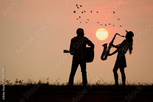 musician play guitar and saxophone with sunset or sunrise background