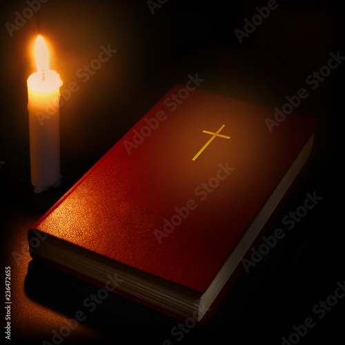 bible and burning candle in the dark