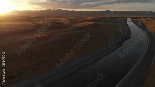 Left to right aerial near sundown over the aqueduct supply fresh water to Californian farms and people.  Golden grass on the hillside serve as a reminder of the extreme drought conditions farmers face photo