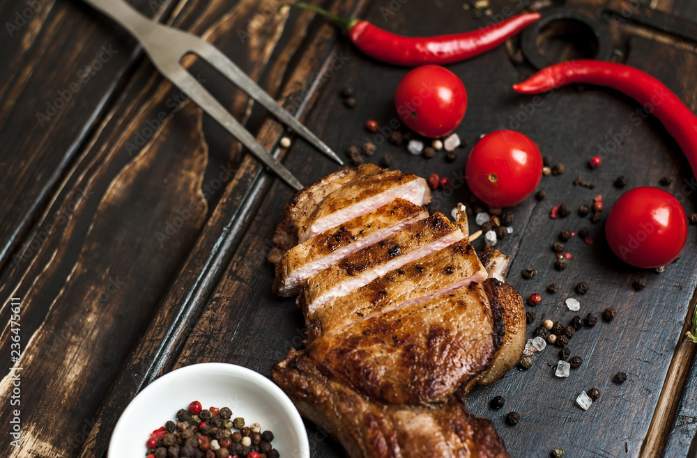 Grilled New York steak with salt and pepper on a dark wooden background