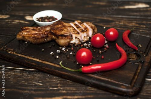 Grilled New York steak with salt and pepper on a dark wooden background