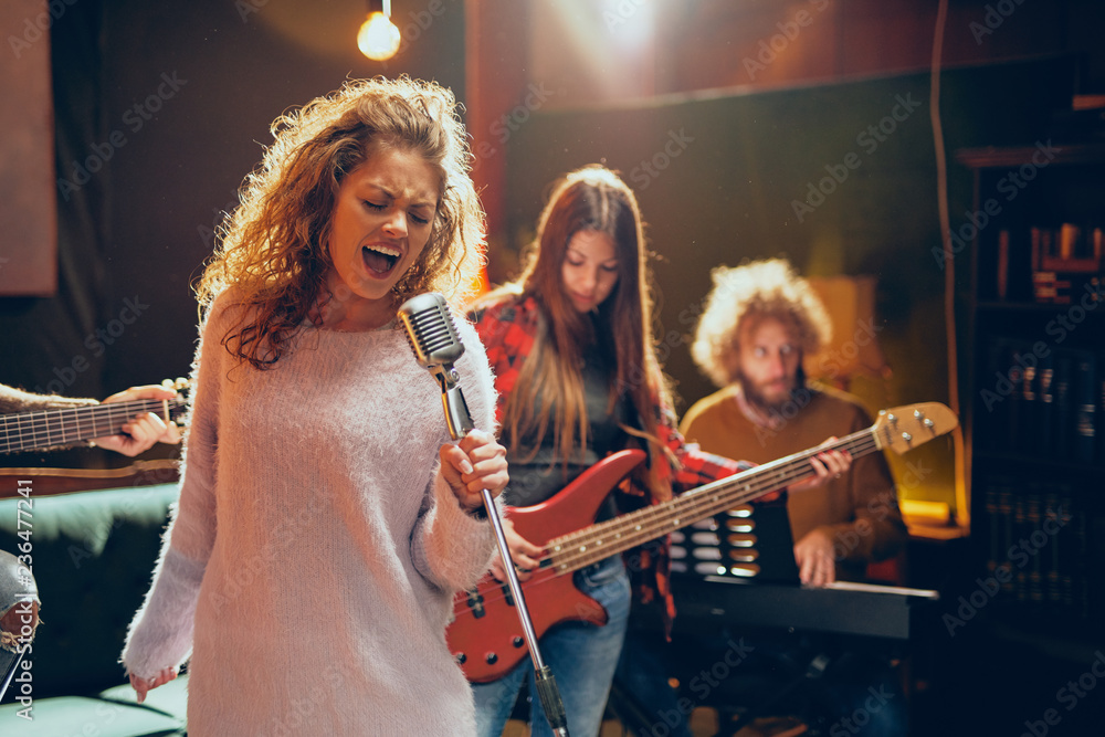 Jazz band preparing for the gig. In foreground woman singing while the rest  of the band playing bass guitar, clavier and acoustic guitar. Home music  studio interior. Stock Photo | Adobe Stock